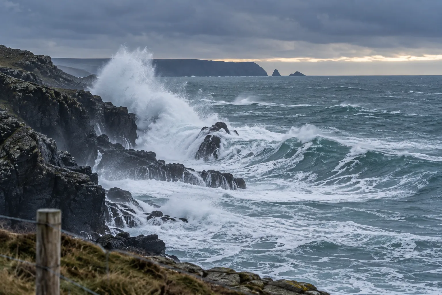 Winter Atlantic swell breaking against a dark headland on the Maine coast